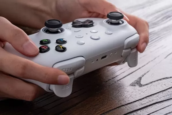 Person holding white Ultimate 2 Wireless Controller on wooden surface